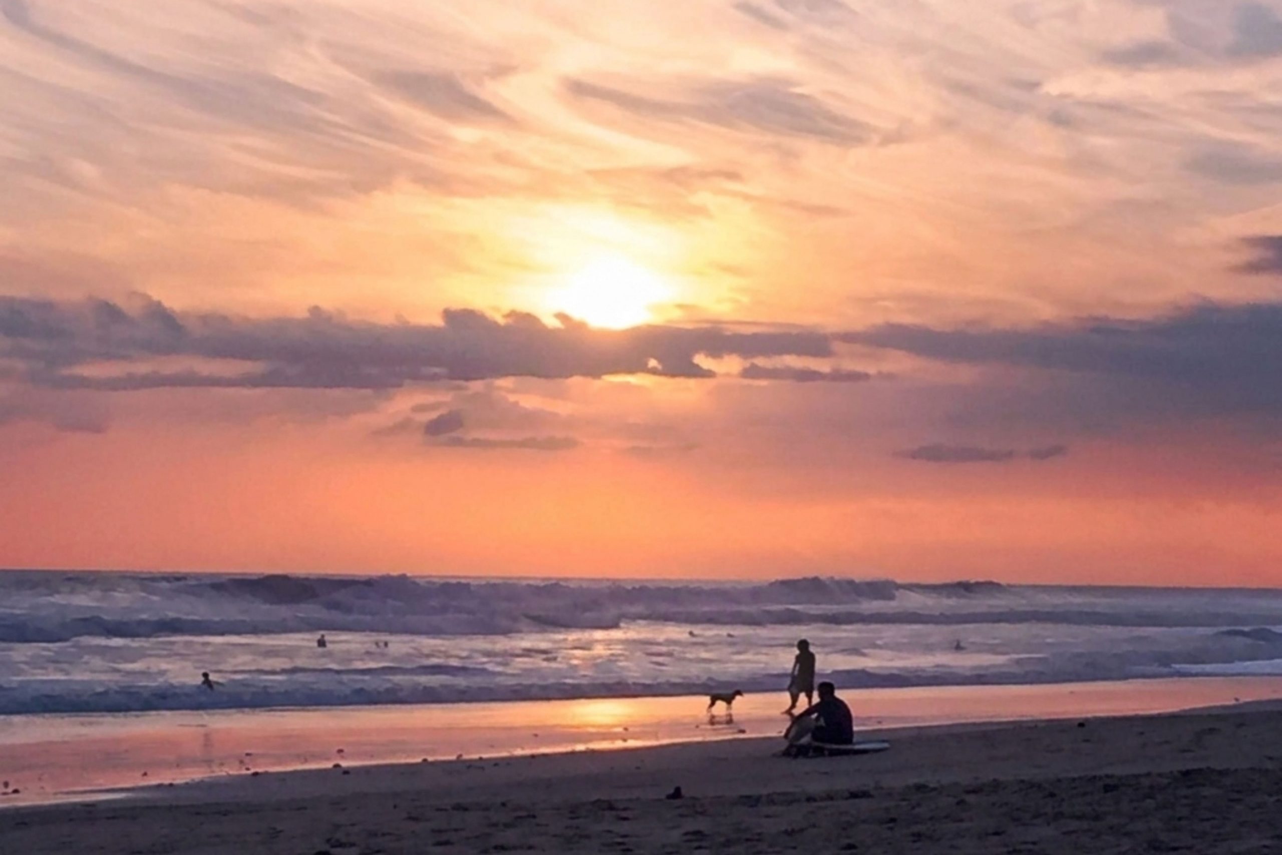 Santa Teresa Costa Rica beach at sunset with surfers and tropical coastline